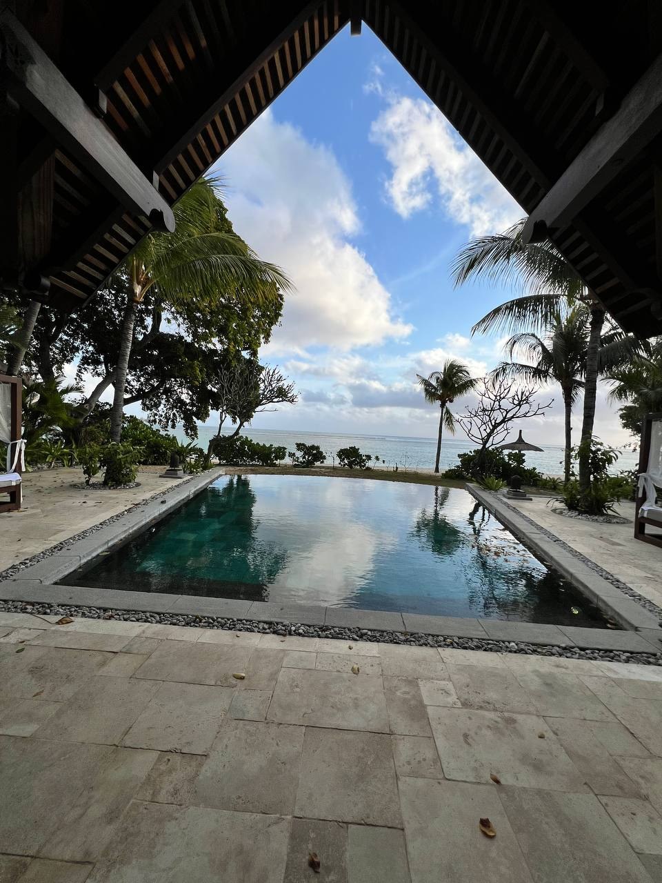 Приватный бассейн виллы с видом на океан сквозь пальмы