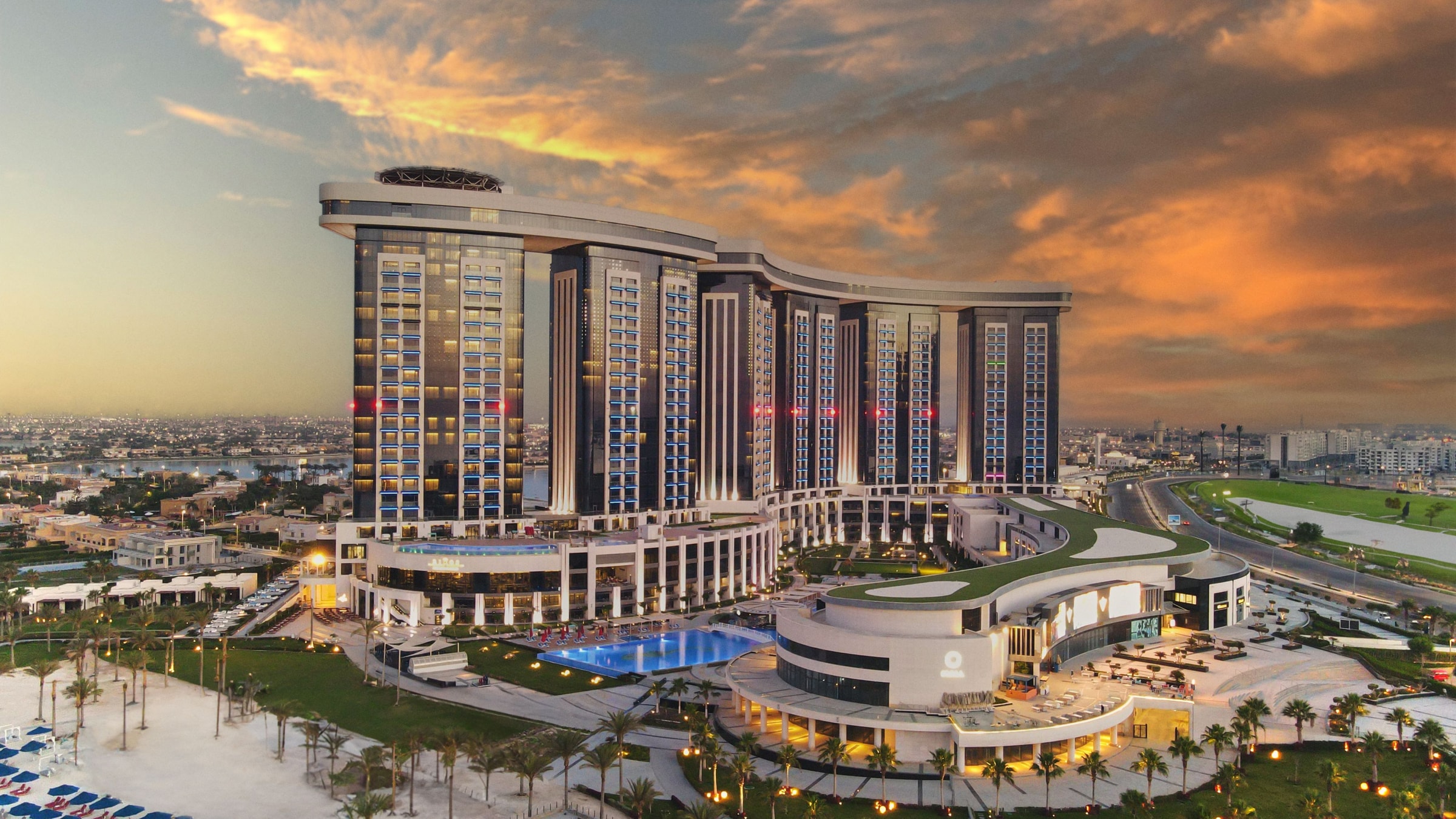 Башни, бассейн и территория Rixos Premium Alamein, вид с высоты на закате